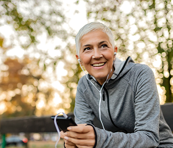 Woman using a phone outdoors after cataract surgery, showcasing enhanced independence post-surgery.