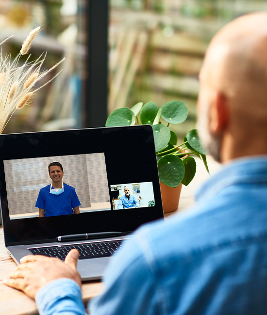 A person in a virtual consultation with Dr. Goel via laptop for LASIK, SMILE, and cataract surgery information.